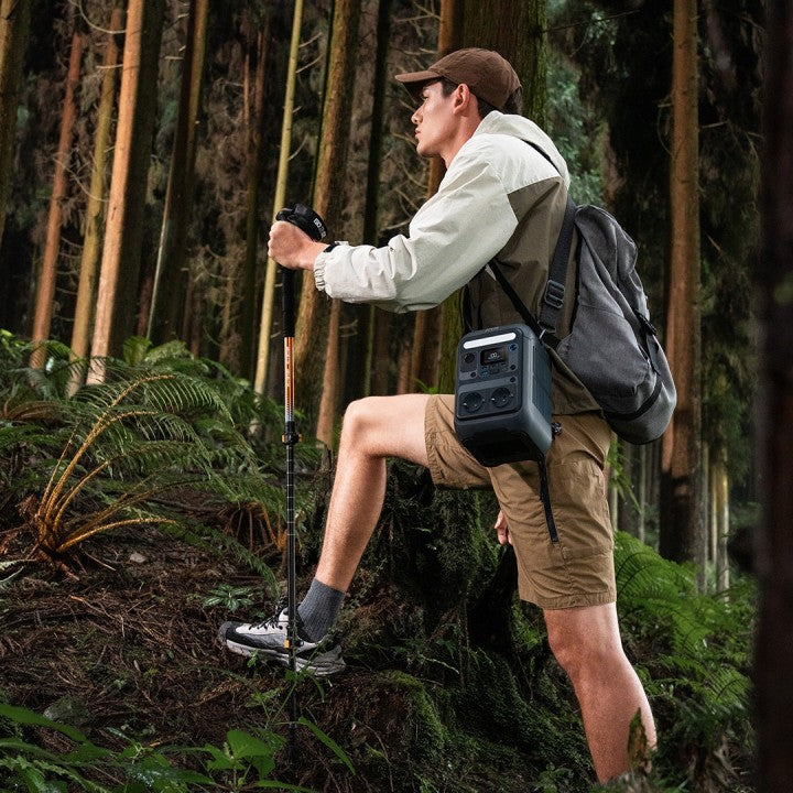 A hiker using the Anker SOLIX C300X 288Wh Power Bank on a trail in a forest.