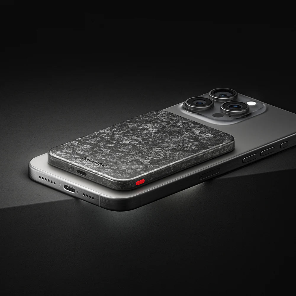 SHARGE CarbonMag Ultra Slim Powerbank 5000 mAh on a smartphone, showcasing its sleek carbon fiber design.
