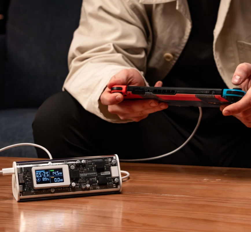 User charging a device with the SHARGE Shargeek 170 power bank, showcasing its transparent design and smart display.